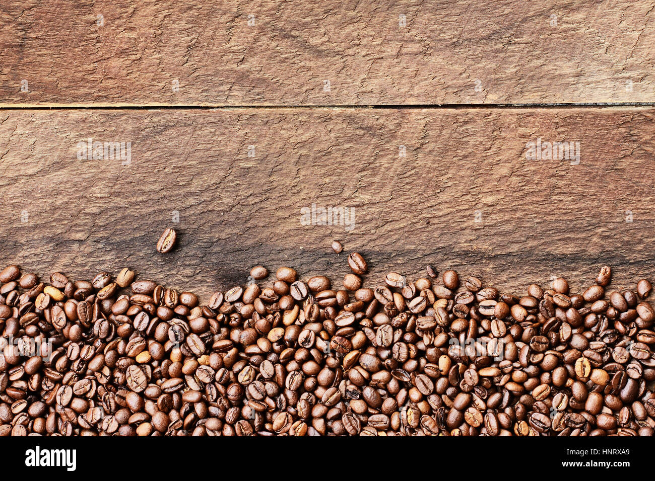Overhead shot looking down on a flatlay image of coffee beans over a rustic wood table top background with copy space. Stock Photo