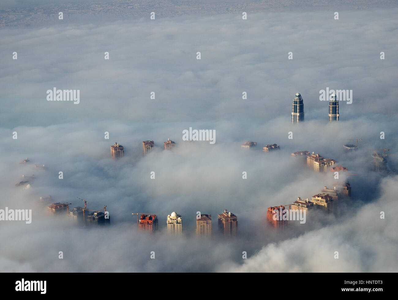 tall buildings rise above ground fog as viewed from above in Doha, Qatar Stock Photo
