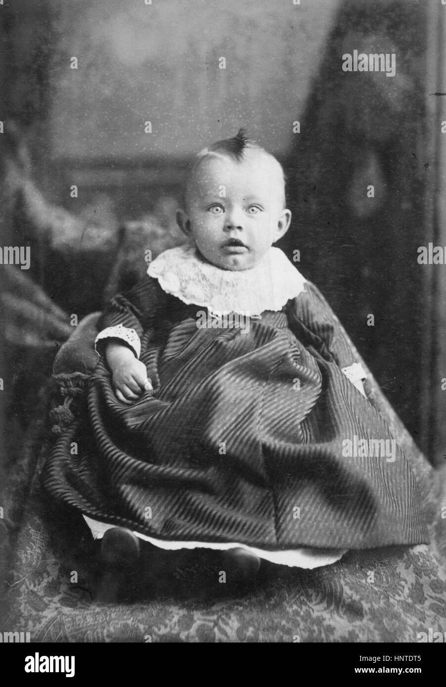 Startled Baby with Kewpie doll hairstyle and doily collar. 1880s.   To see my other child-related vintage images, Search:  Prestor  vintage  kids Stock Photo