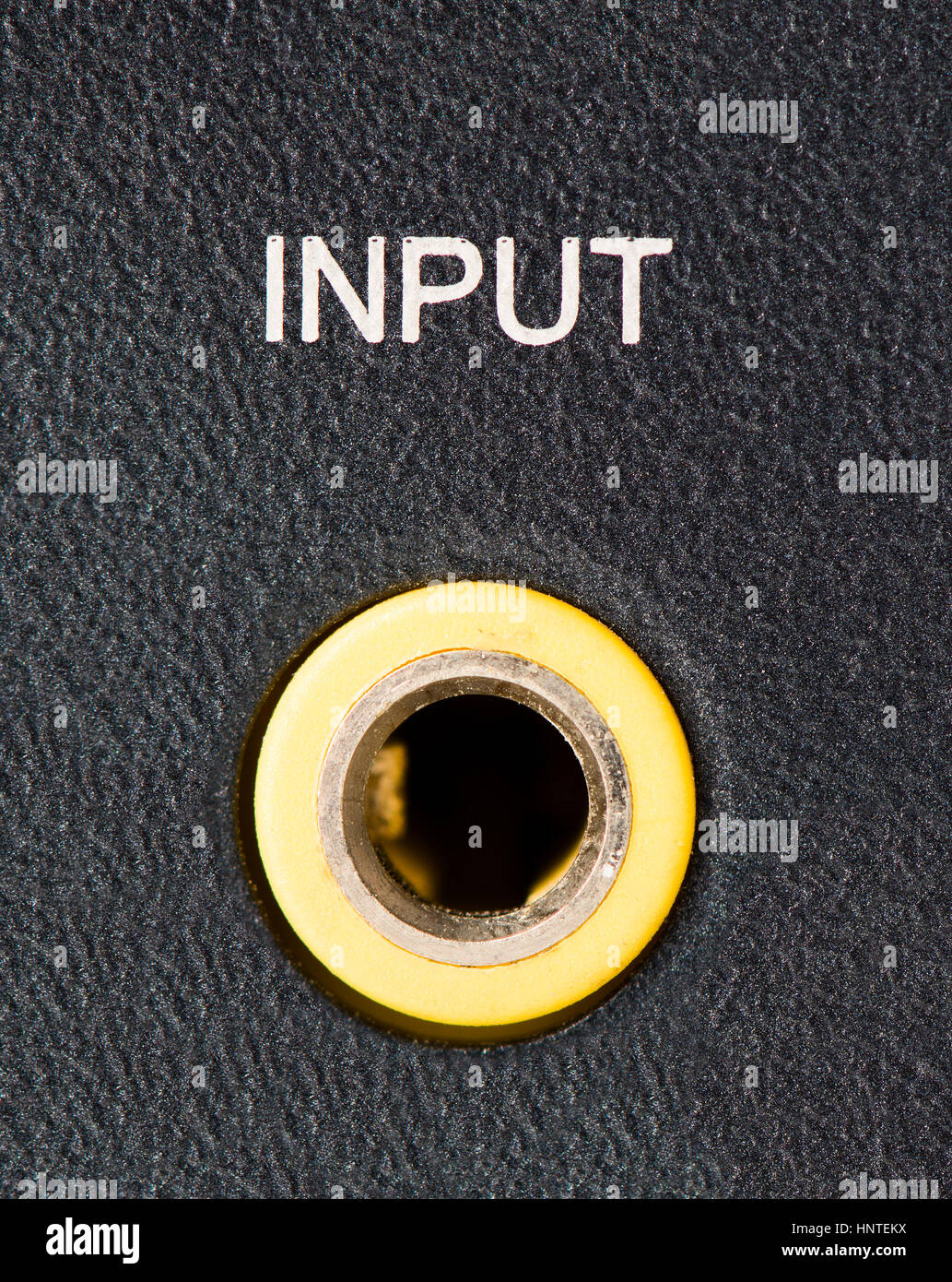 Closeup of a yellow headphone/auxiliary port on the back of a computer speaker. Stock Photo
