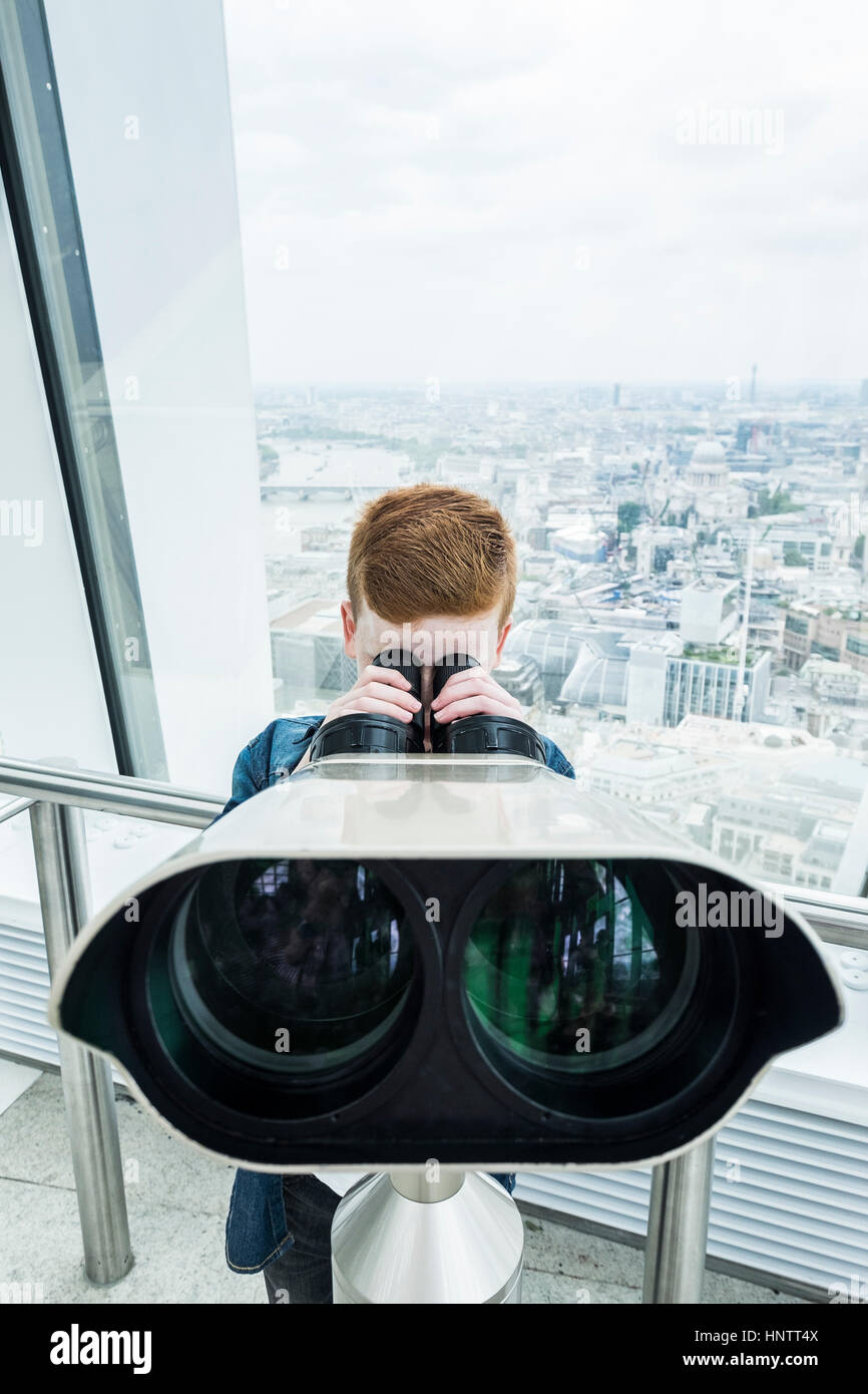 A boy looking through binoculars from a viewing platform. Stock Photo
