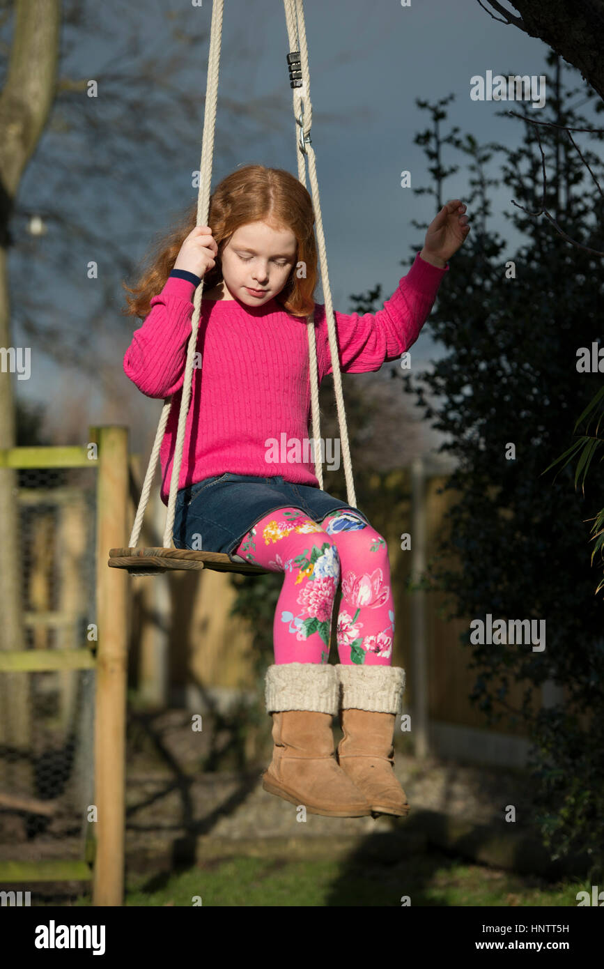 Portrait of a little girl on a garden swing Stock Photo - Alamy