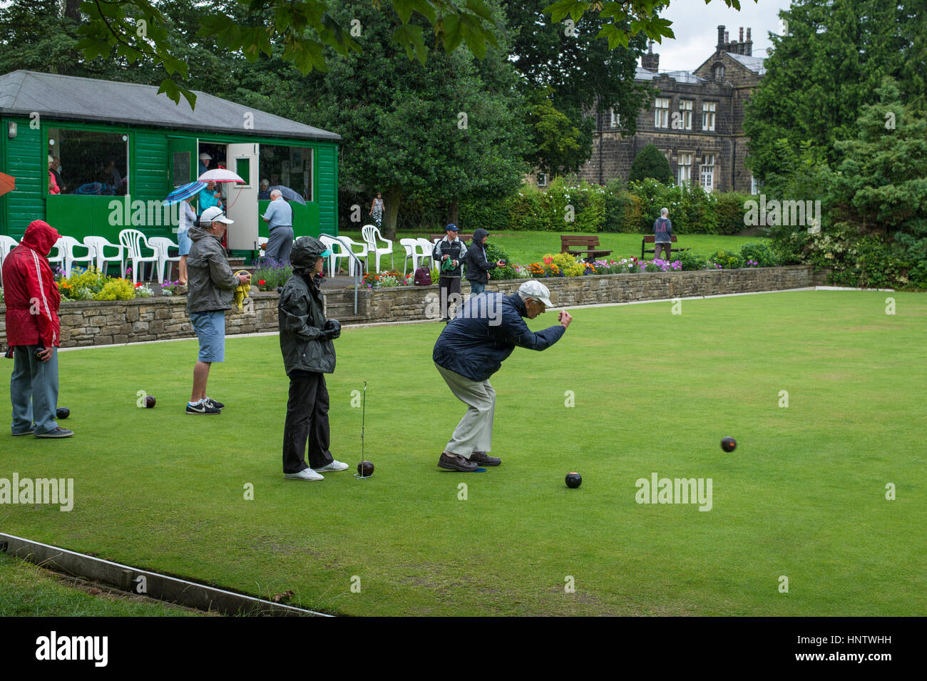 Competitors and spectators (in the rain) at a crown green bowling match on the village bowling green - Burley In Wharfedale, West Yorkshire, England. Stock Photo