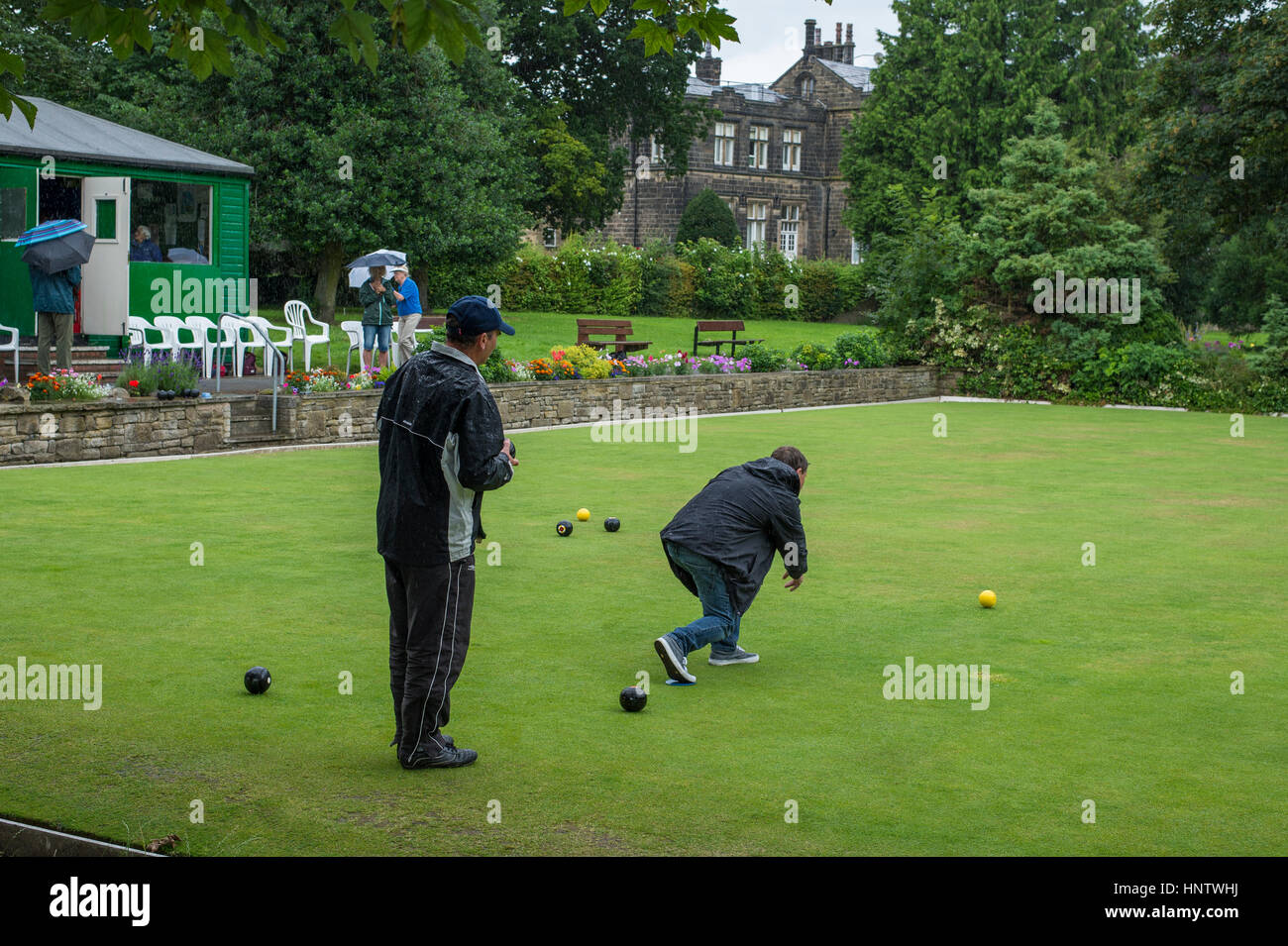 Competitors and spectators (in the rain) at a crown green bowling match on the village bowling green - Burley In Wharfedale, West Yorkshire, England. Stock Photo