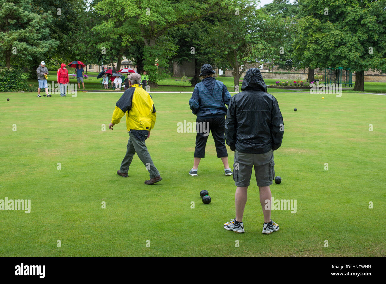 Competitors and spectators (in the rain) at a crown green bowling match on the village bowling green - Burley In Wharfedale, West Yorkshire, England. Stock Photo