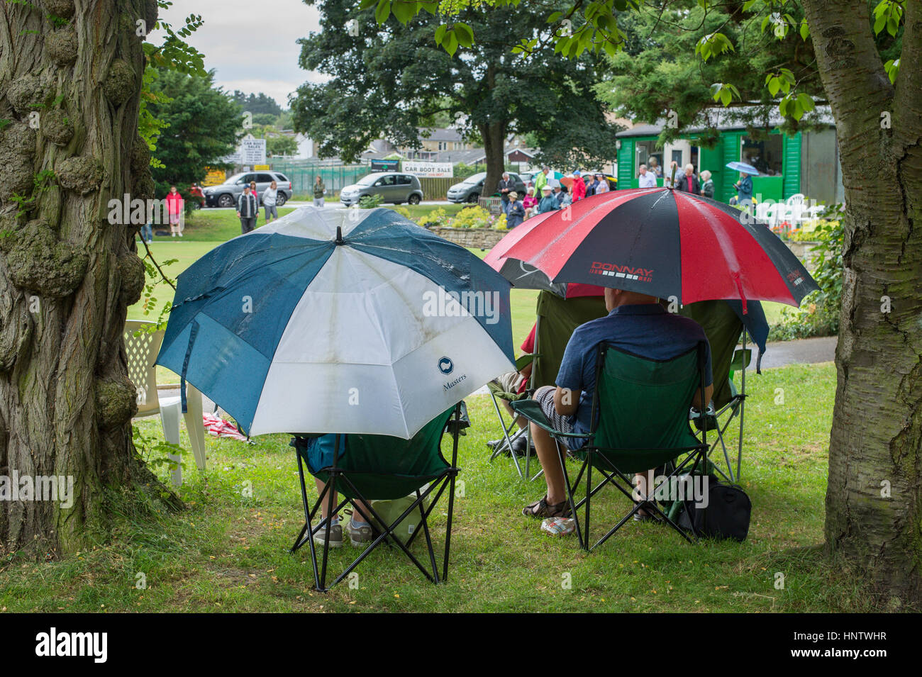 Competitors and spectators (in the rain) at a crown green bowling match on the village bowling green - Burley In Wharfedale, West Yorkshire, England. Stock Photo
