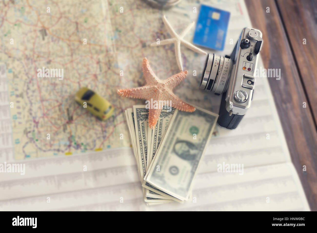 car figurine, camera, compass, credit card, banknote money, globe, map, starfish figurine on wooden table for use as traveling concept (vintage tone a Stock Photo