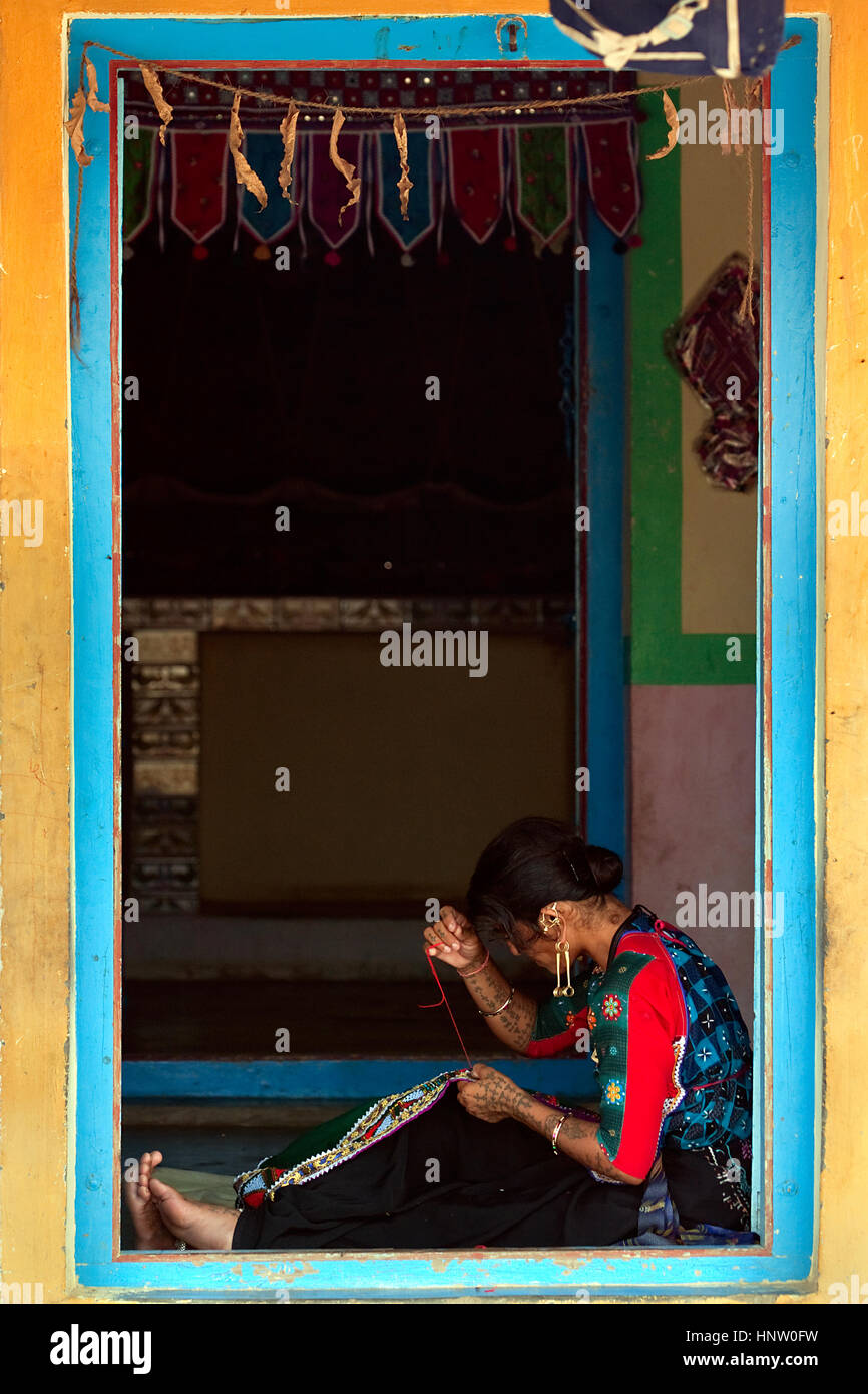 A Kutch/Kachchh woman sitting on the floor at the open door of the house, stiching, doing handicraft Stock Photo