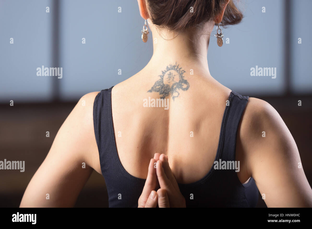 Young woman making namaste behind the back, studio evening pract Stock Photo