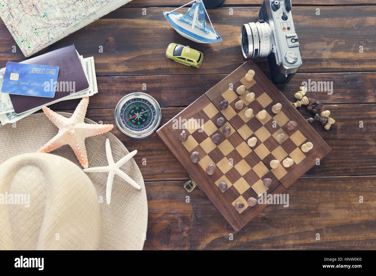 chessboard, hat, compass, passport, credit card, banknote money, camera, map, car ship and starfish figurine on wooden table for use as traveling conc Stock Photo