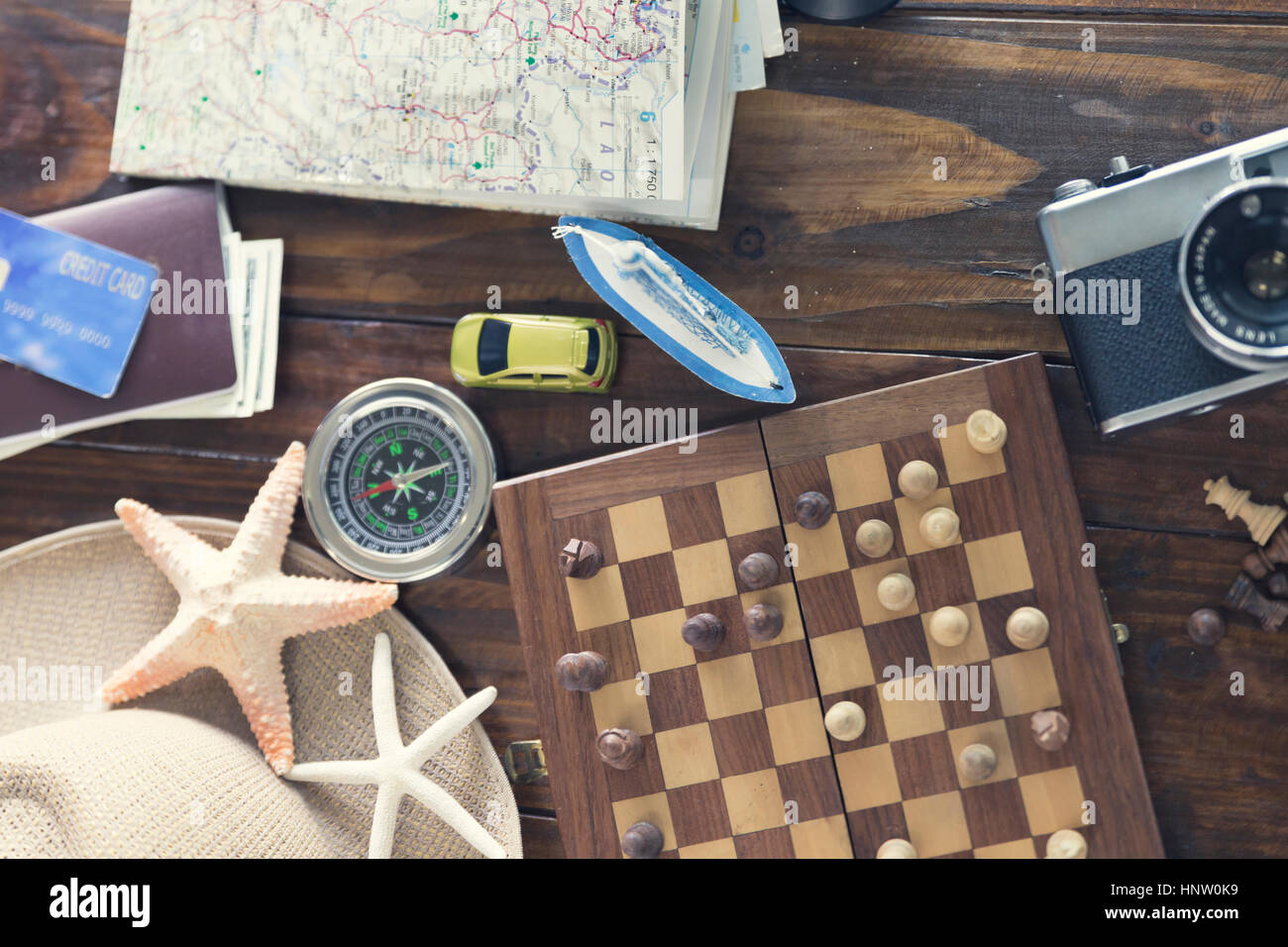 chessboard, hat, compass, passport, credit card, banknote money, camera, map, car ship and starfish figurine on wooden table for use as traveling conc Stock Photo
