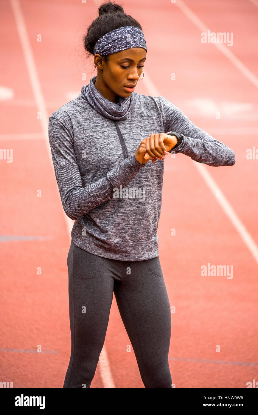 Black woman checking smart watch on track Stock Photo