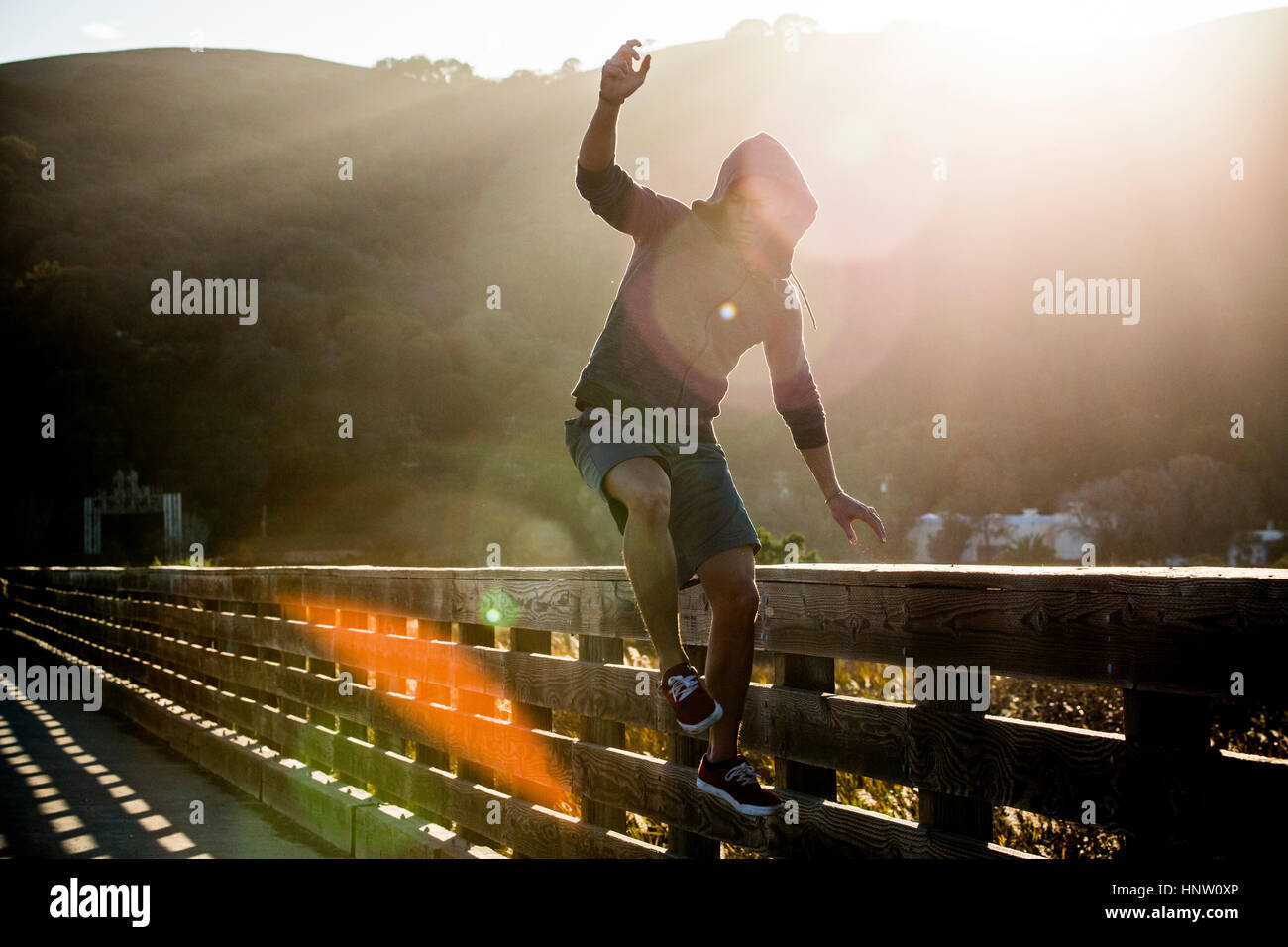 Mixed Race man jumping near railing on footbridge Stock Photo