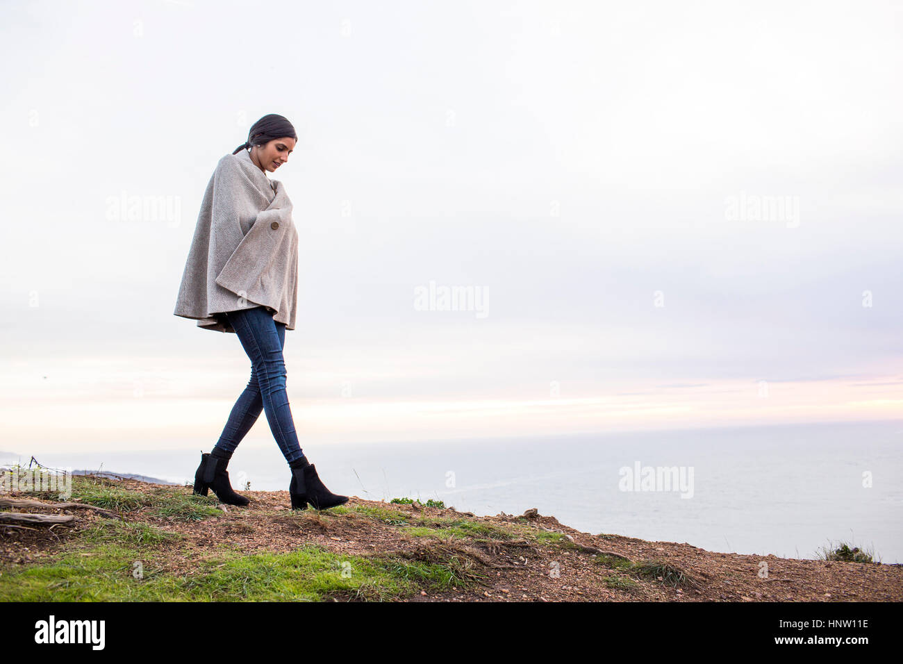 Indian woman wearing poncho walking on hill Stock Photo