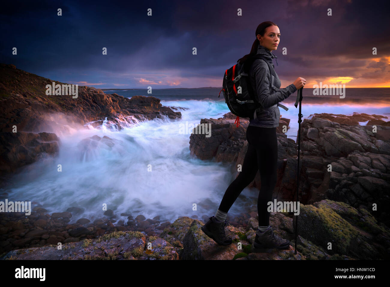 Caucasian woman hiking on rocks near ocean Stock Photo