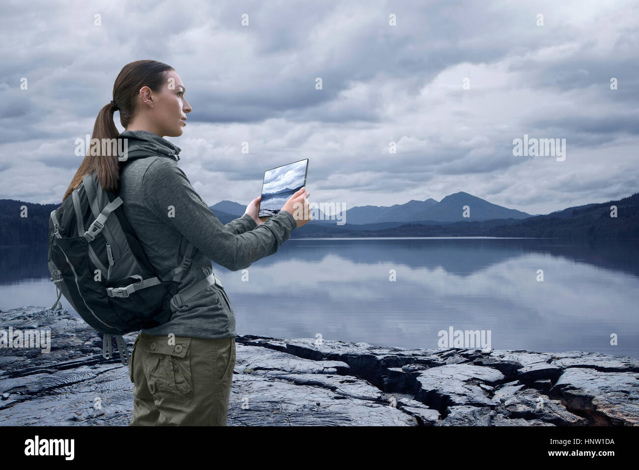Caucasian woman photographing mountain lake with digital tablet Stock Photo