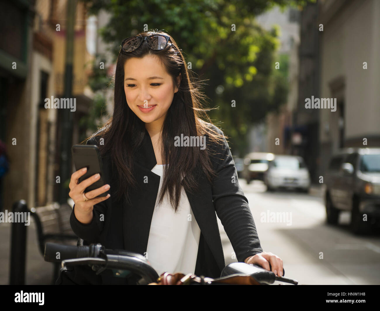 Chinese businesswoman on bicycle texting on cell phone Stock Photo