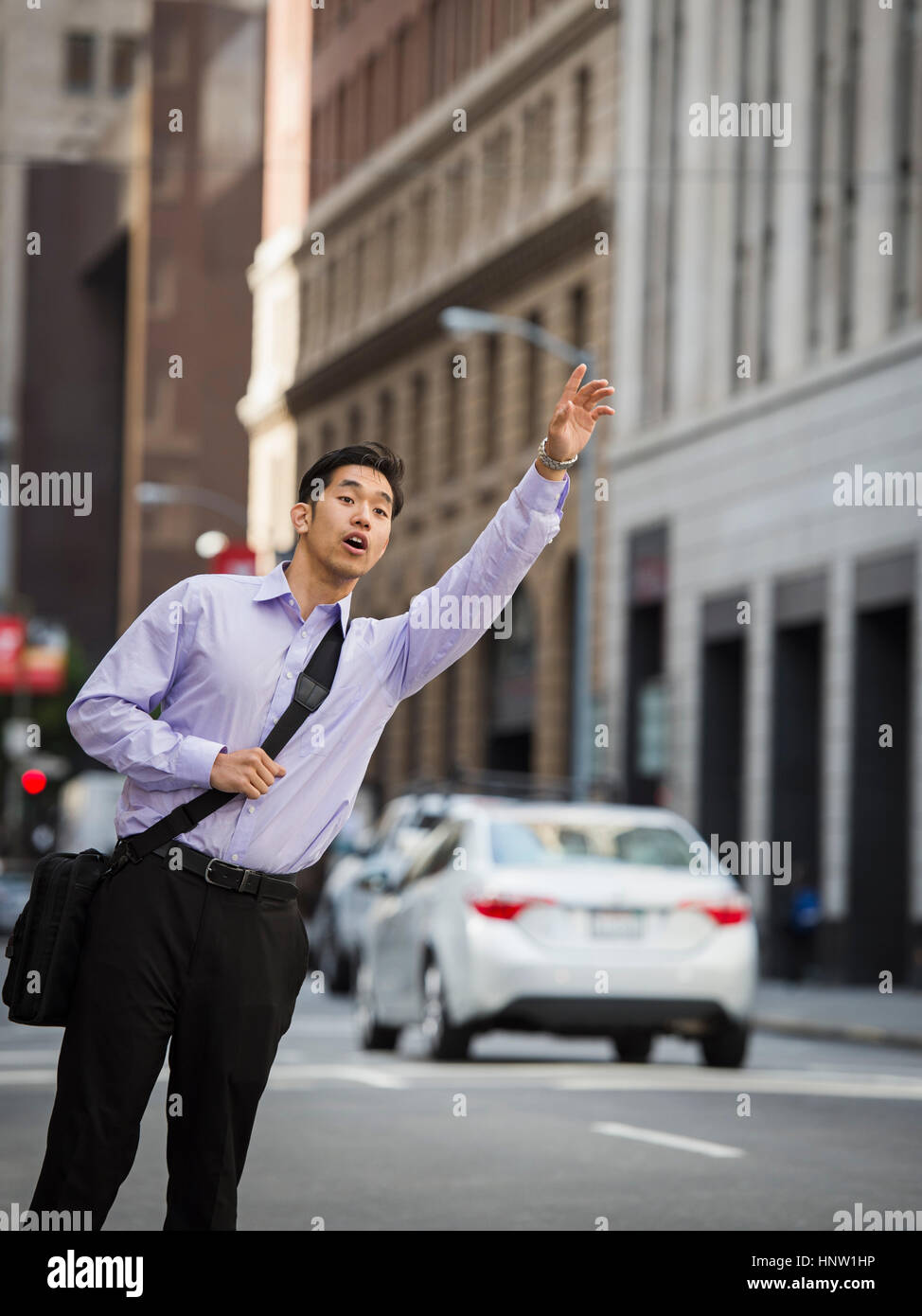 Chinese businessman hailing taxi in city Stock Photo