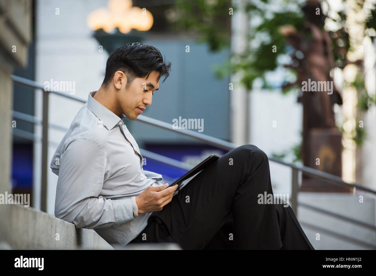 Chinese businessman reading digital tablet on staircase Stock Photo