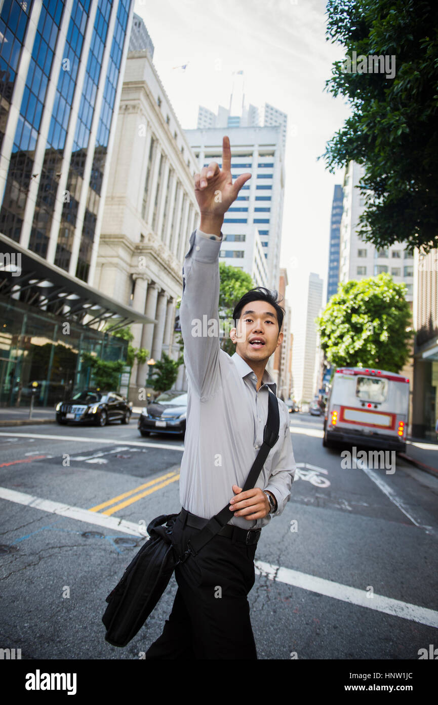 Chinese businessman hailing taxi in city Stock Photo