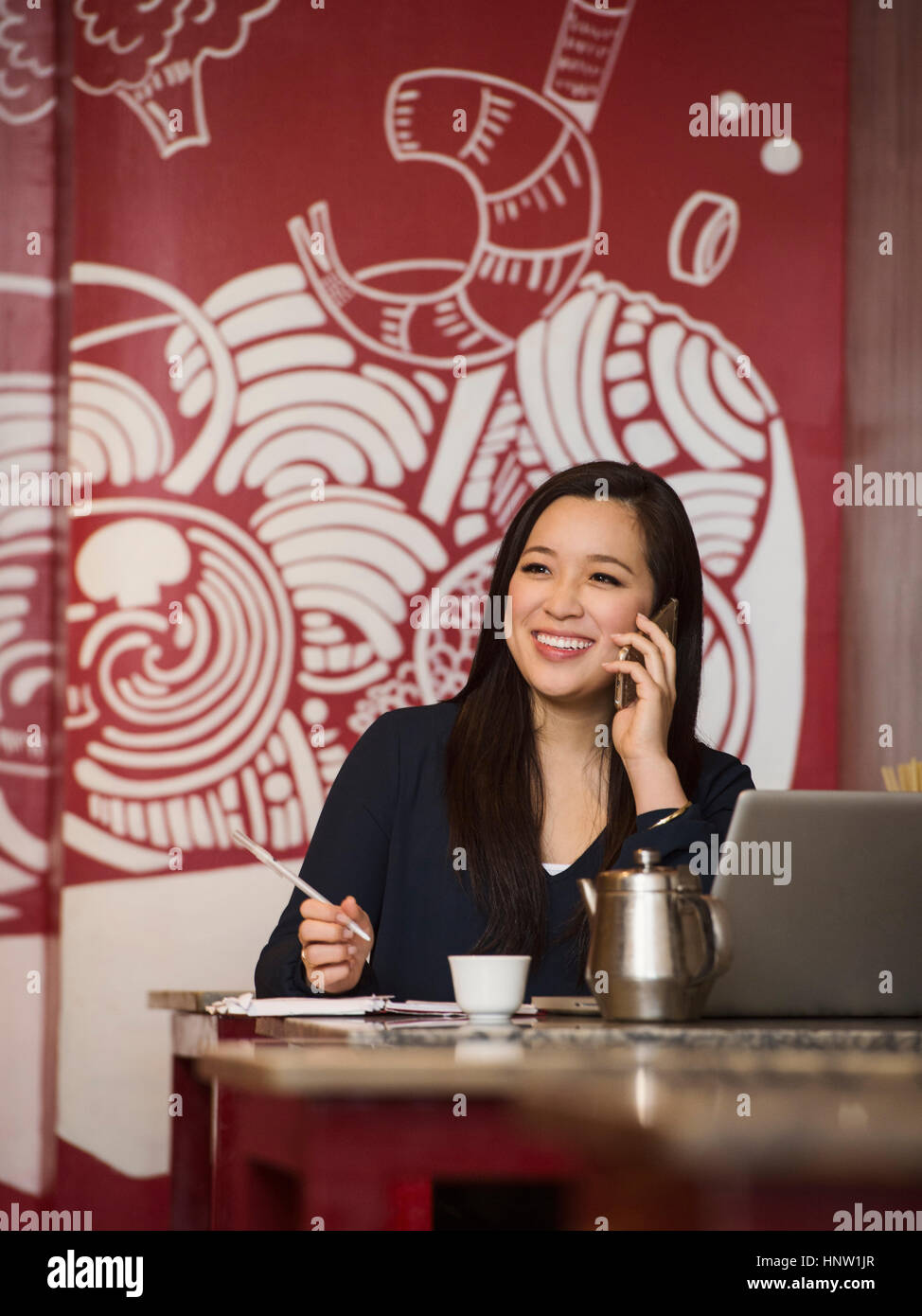 Chinese businesswoman talking on cell phone in restaurant Stock Photo