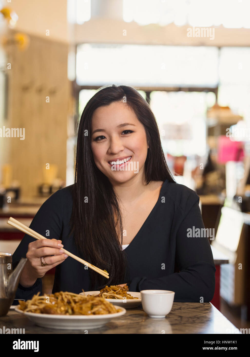 Chinese woman eating with chopsticks in restaurant Stock Photo Alamy