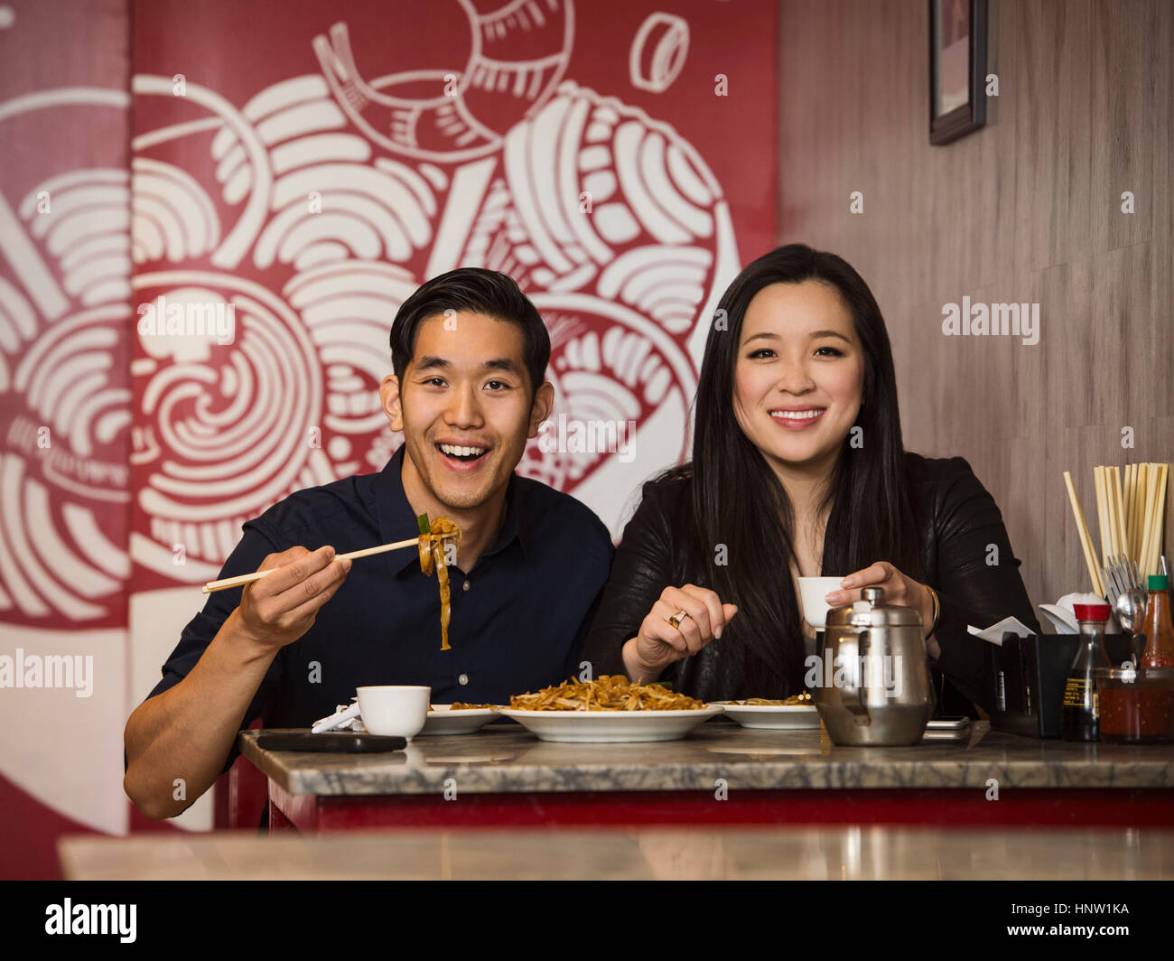 Smiling Chinese couple posing in restaurant Stock Photo