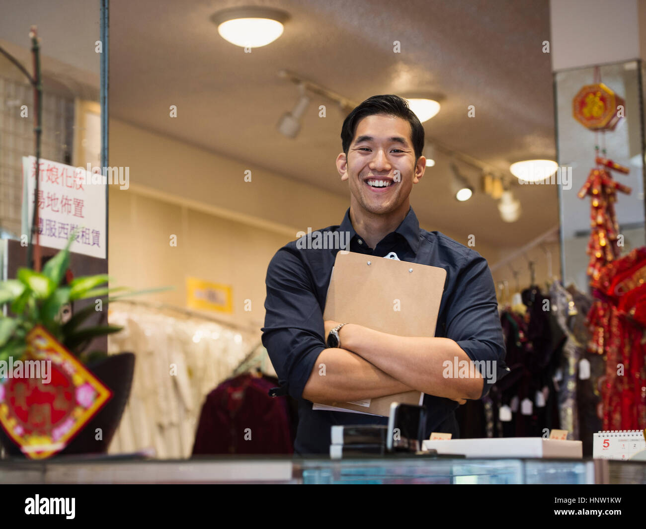 Smiling Chinese man posing with clipboard in store Stock Photo