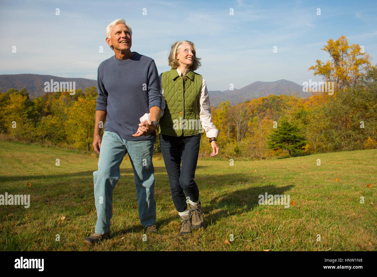 Older Caucasian couple walking in field Stock Photo