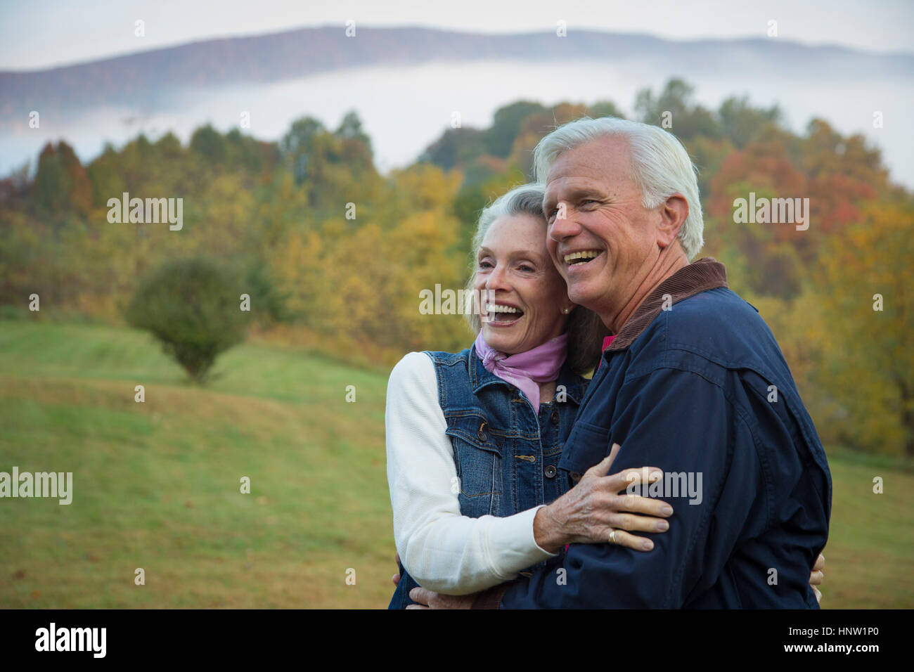 Older Caucasian couple hugging in field Stock Photo