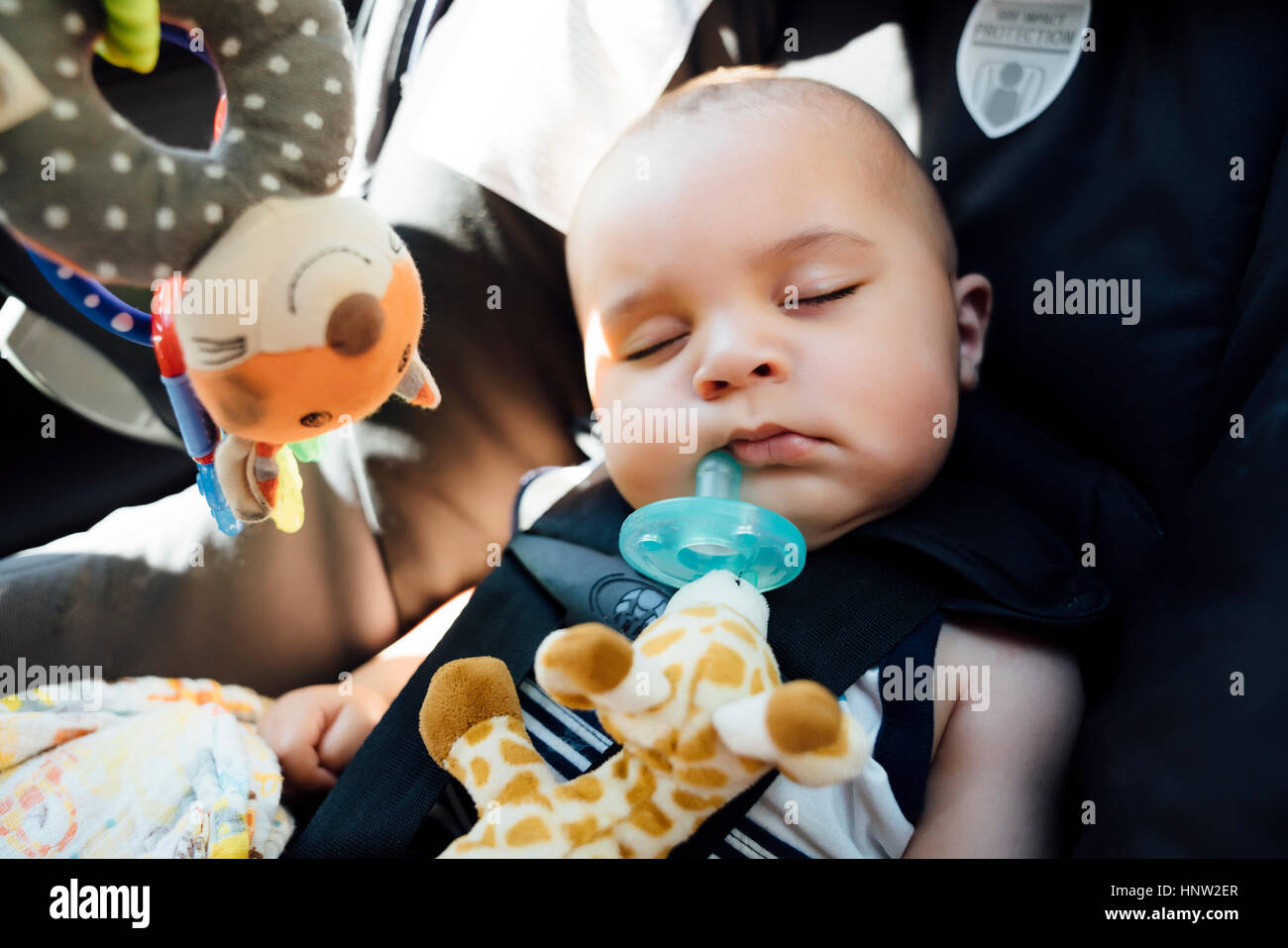 Mixed Race baby boy with pacifier sleeping in car seat Stock Photo