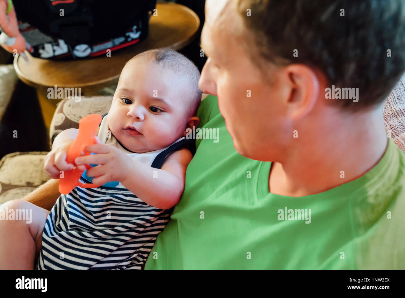 Father holding baby son playing with toy Stock Photo