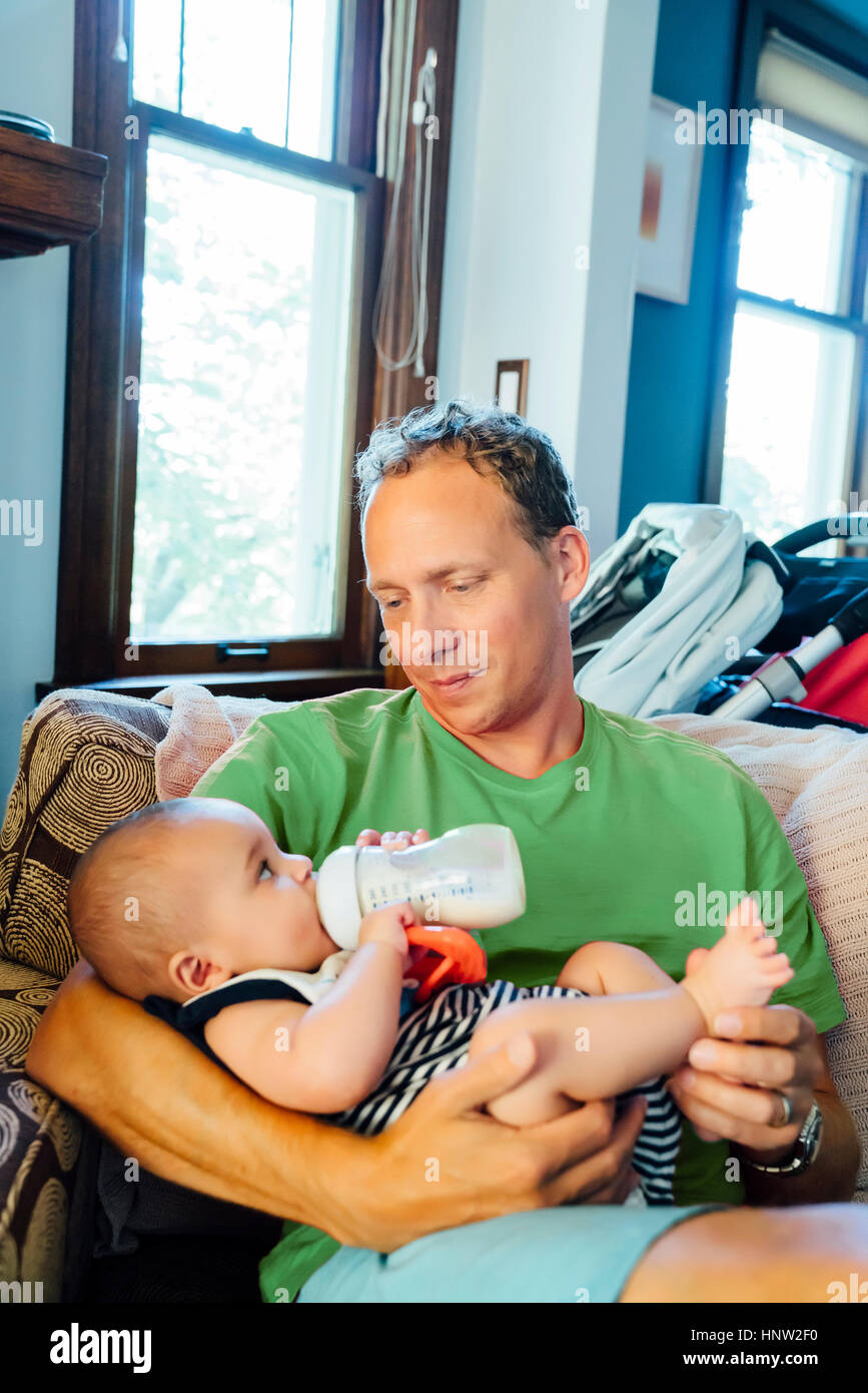 Father holding baby son drinking milk from bottle Stock Photo