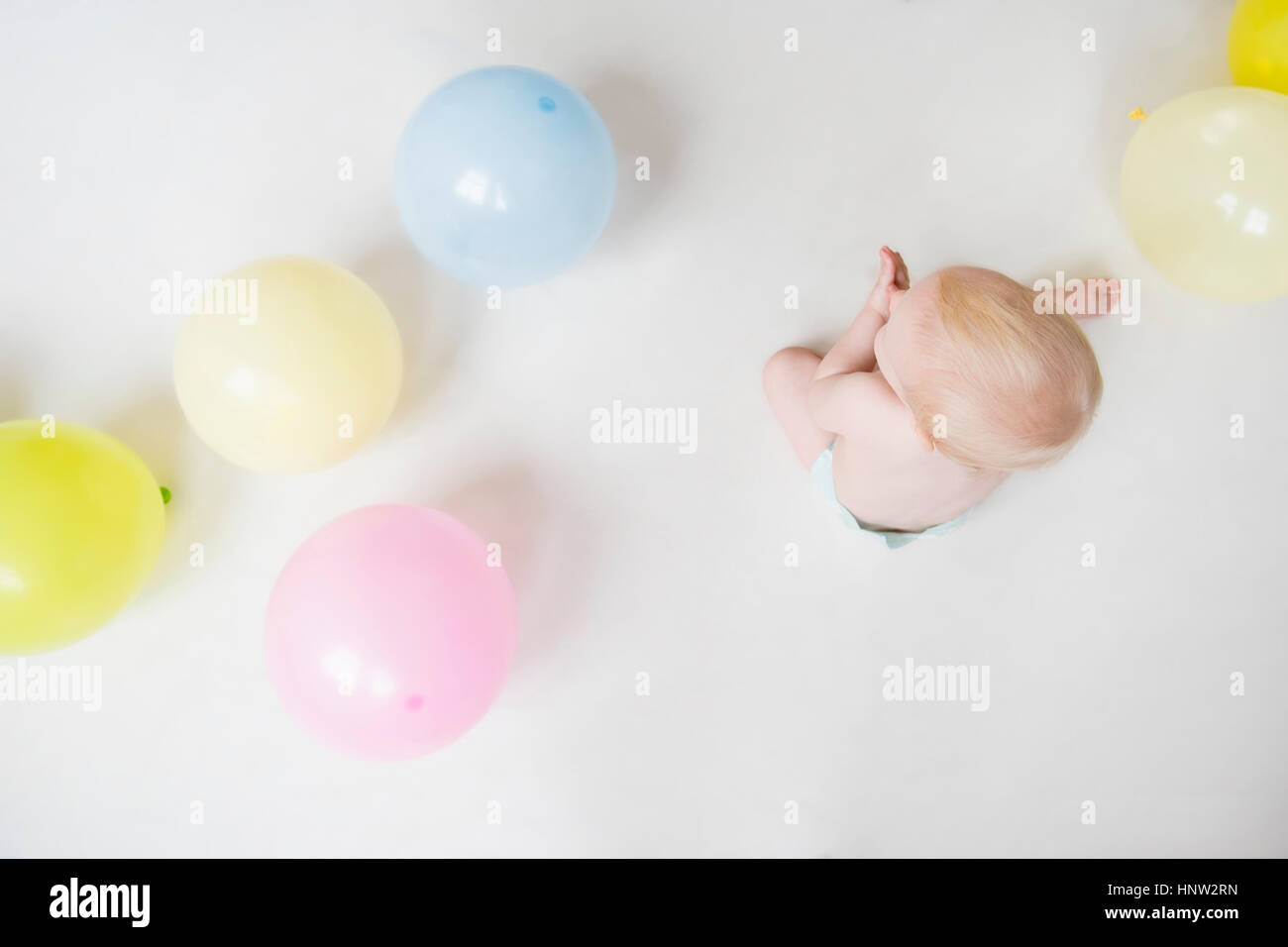 Caucasian baby boy sitting on floor with balloons Stock Photo