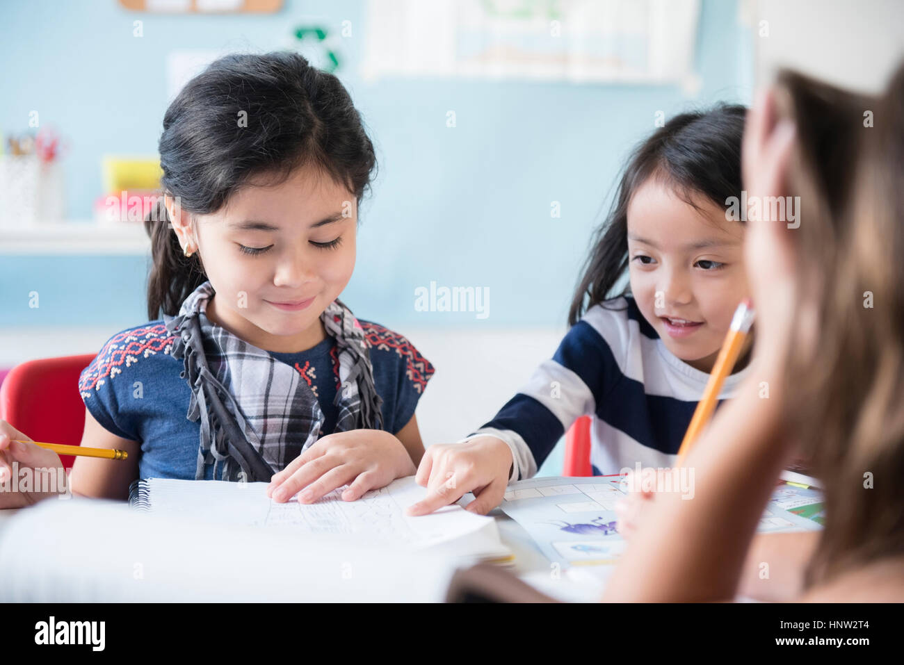 Girls reading notebook in classroom Stock Photo