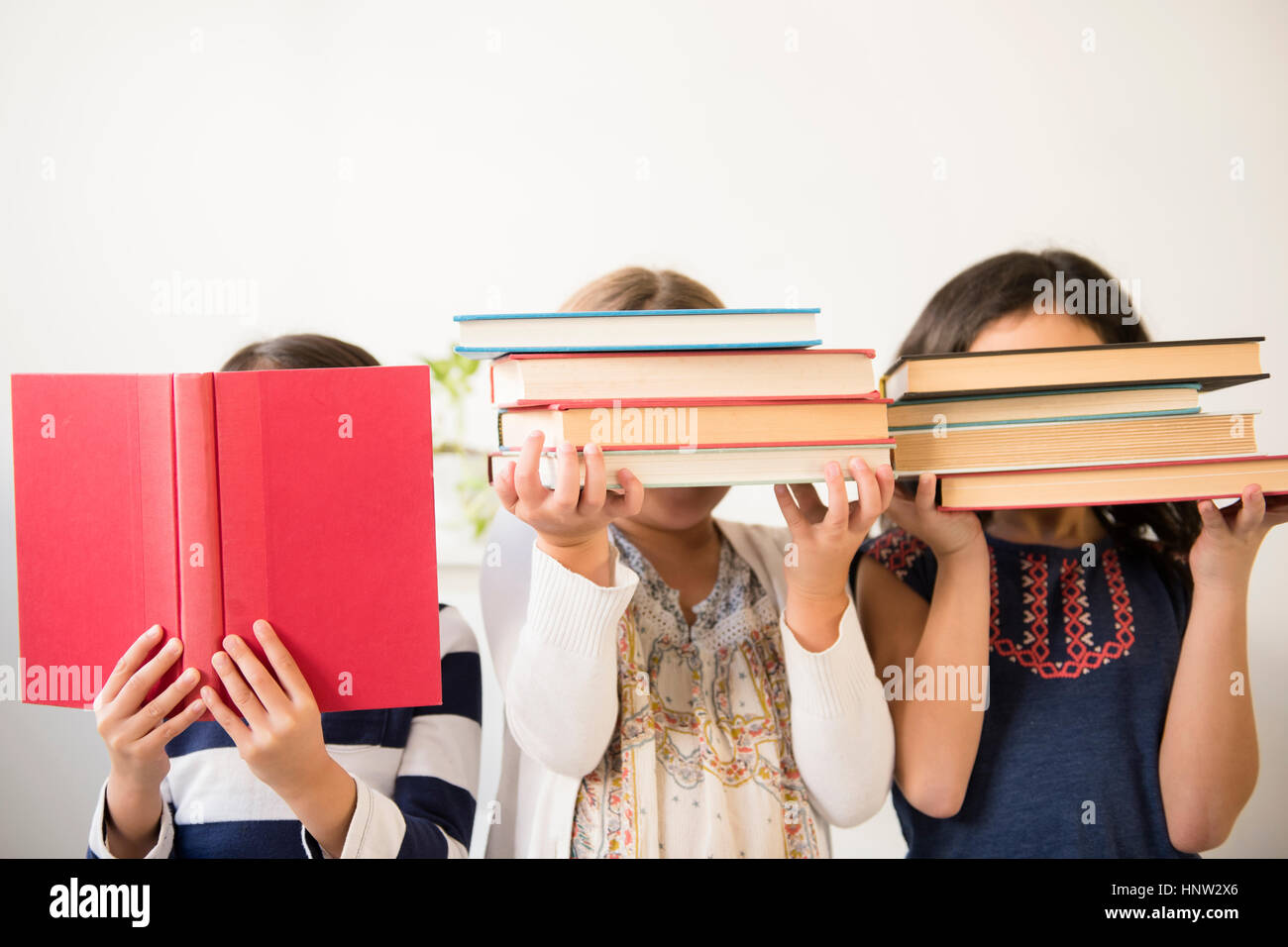 Girls holding books in front of faces Stock Photo