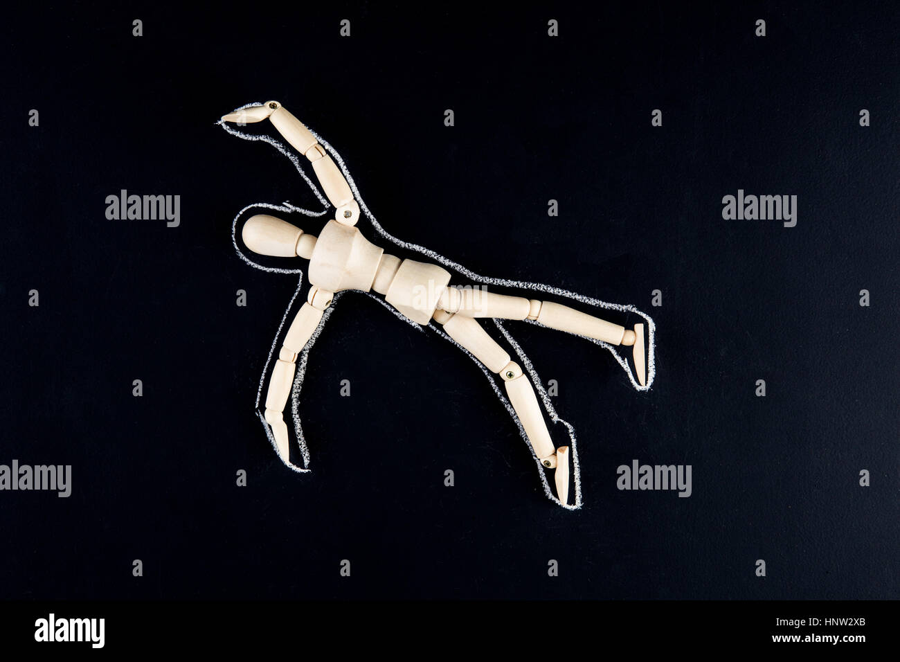 Wooden dummy figurine laying on the floor with chalk outline - crime or suicide concept Stock Photo