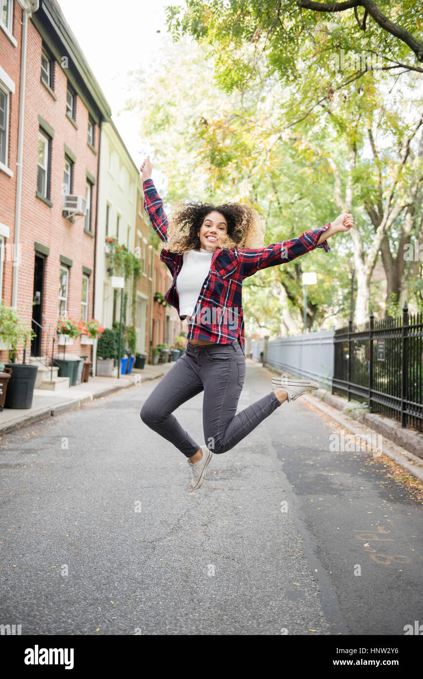 Mixed Race woman jumping for joy in city Stock Photo