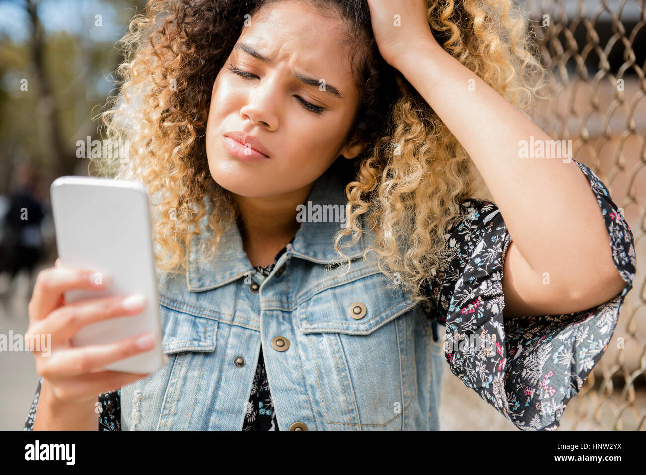 Unhappy Mixed Race woman texting on cell phone Stock Photo