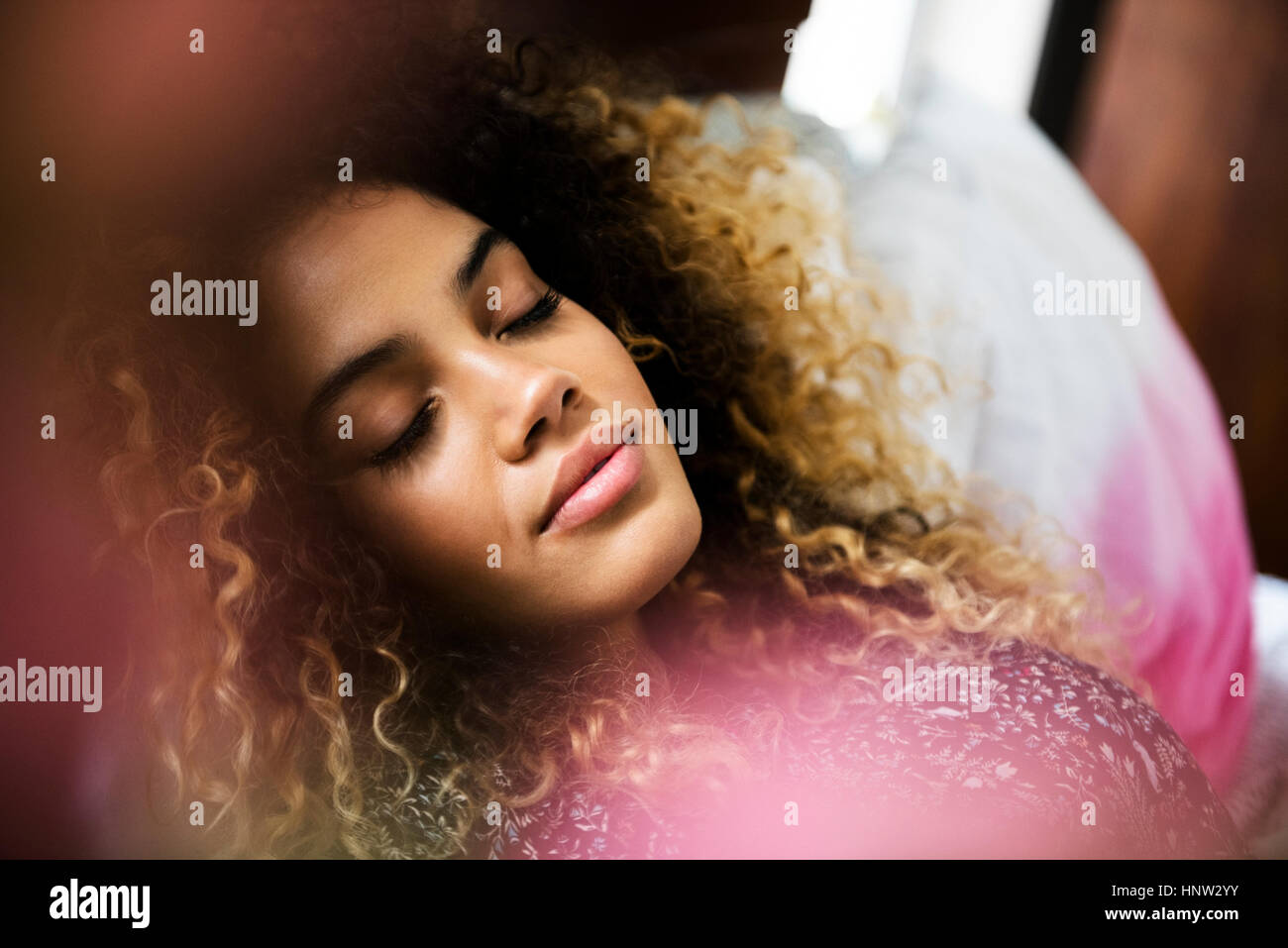 Mixed Race woman relaxing on bed Stock Photo