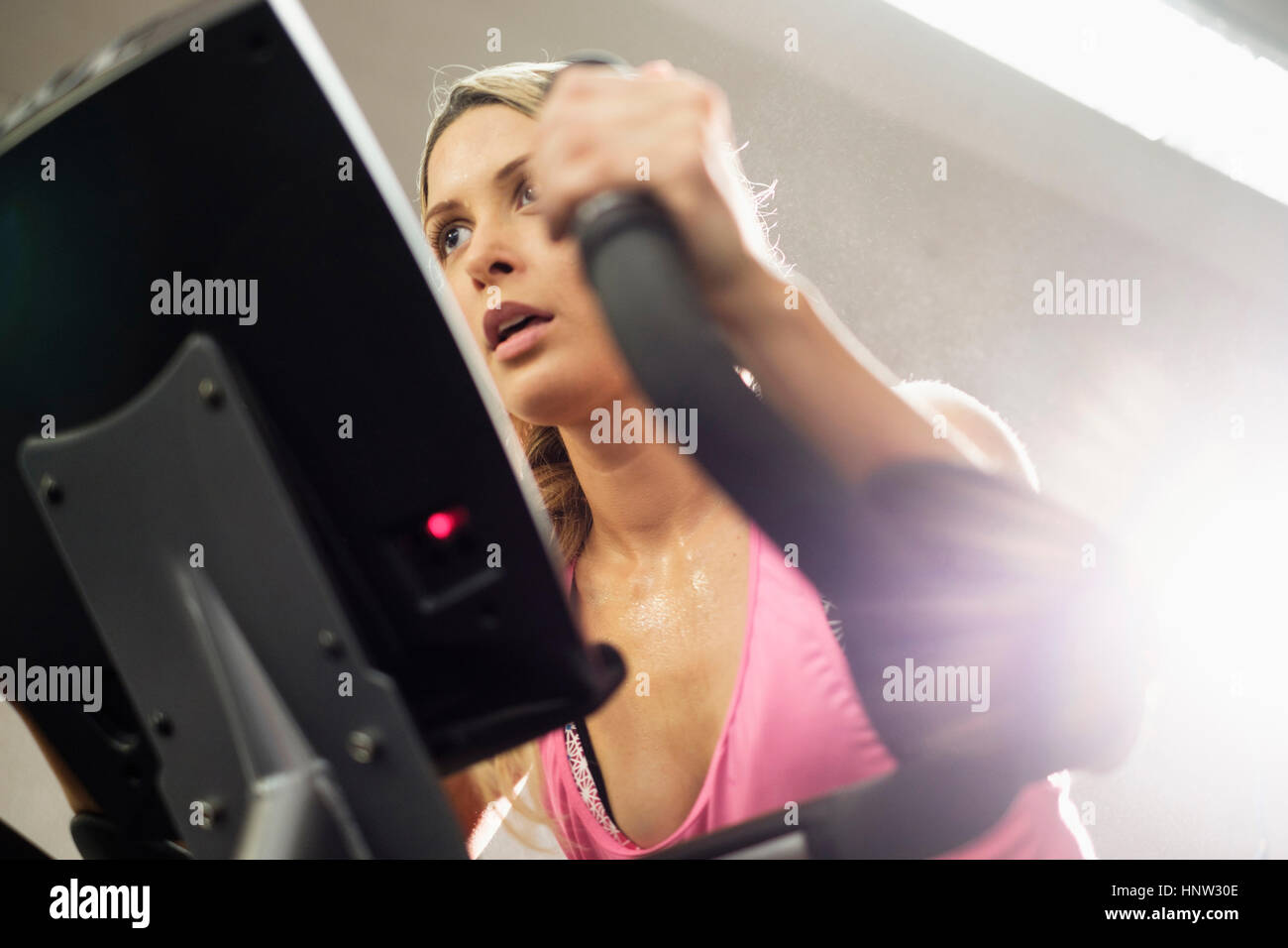 Mixed Race woman riding stationary bicycle Stock Photo