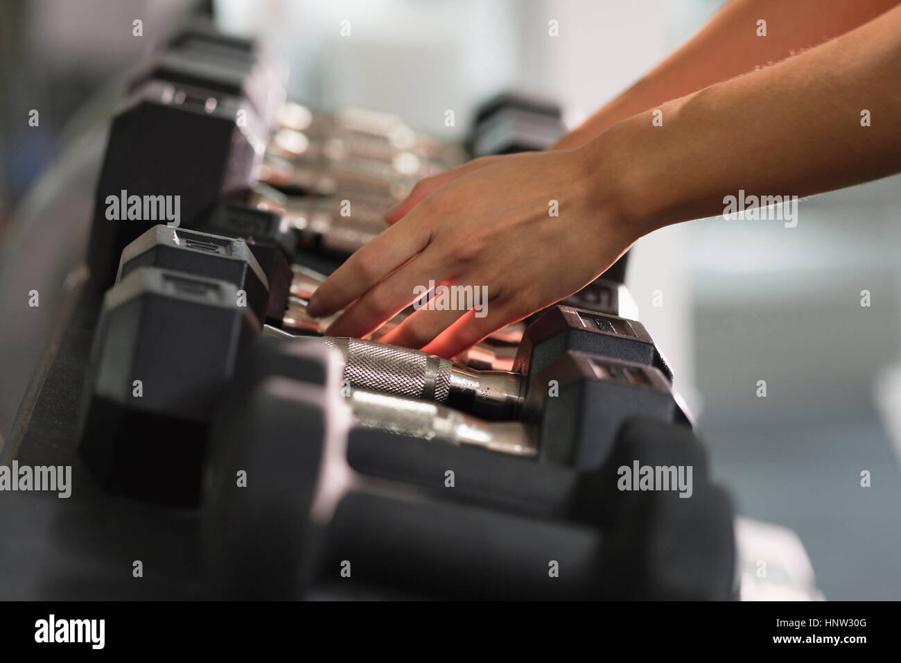 Hands of Mixed Race woman reaching for dumbbells Stock Photo