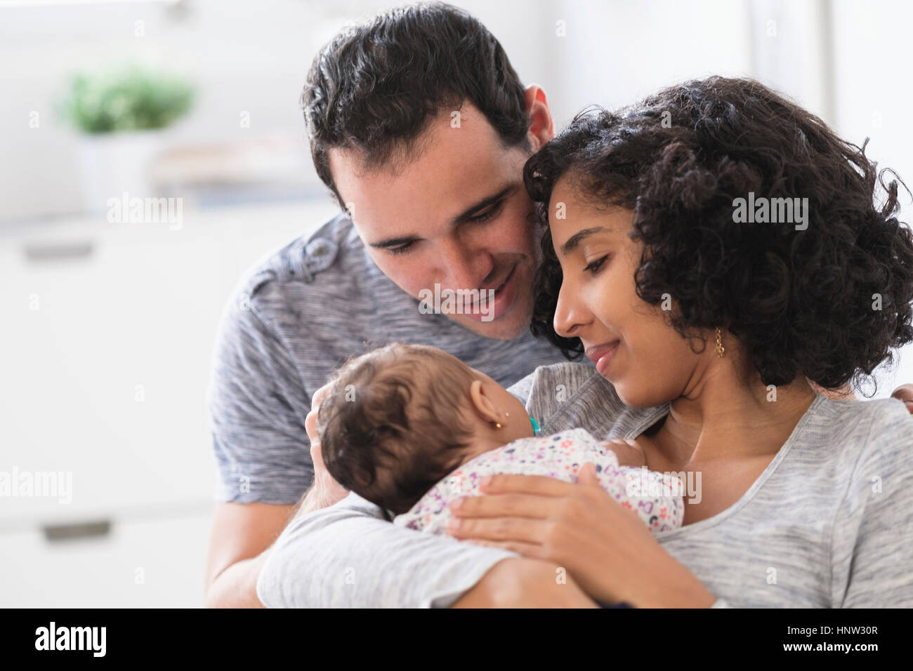 Hispanic mother and father admiring baby daughter Stock Photo