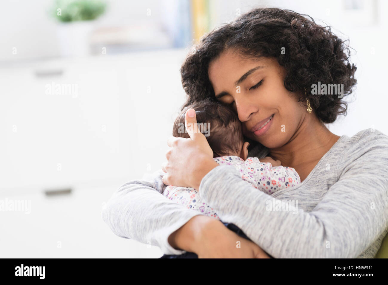Hispanic mother hugging baby daughter Stock Photo