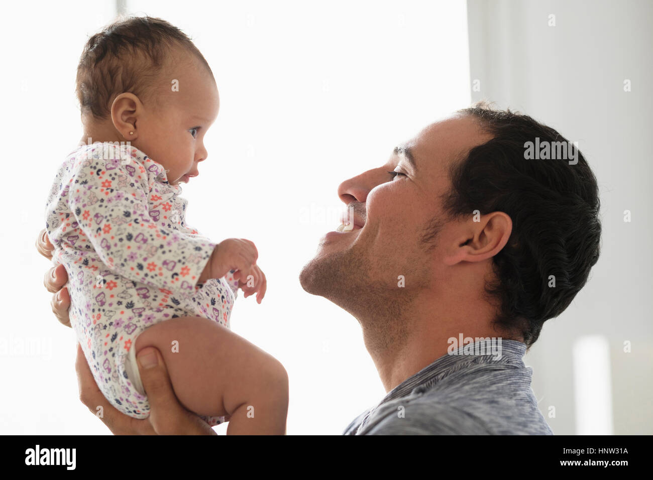 Hispanic father lifting baby daughter Stock Photo