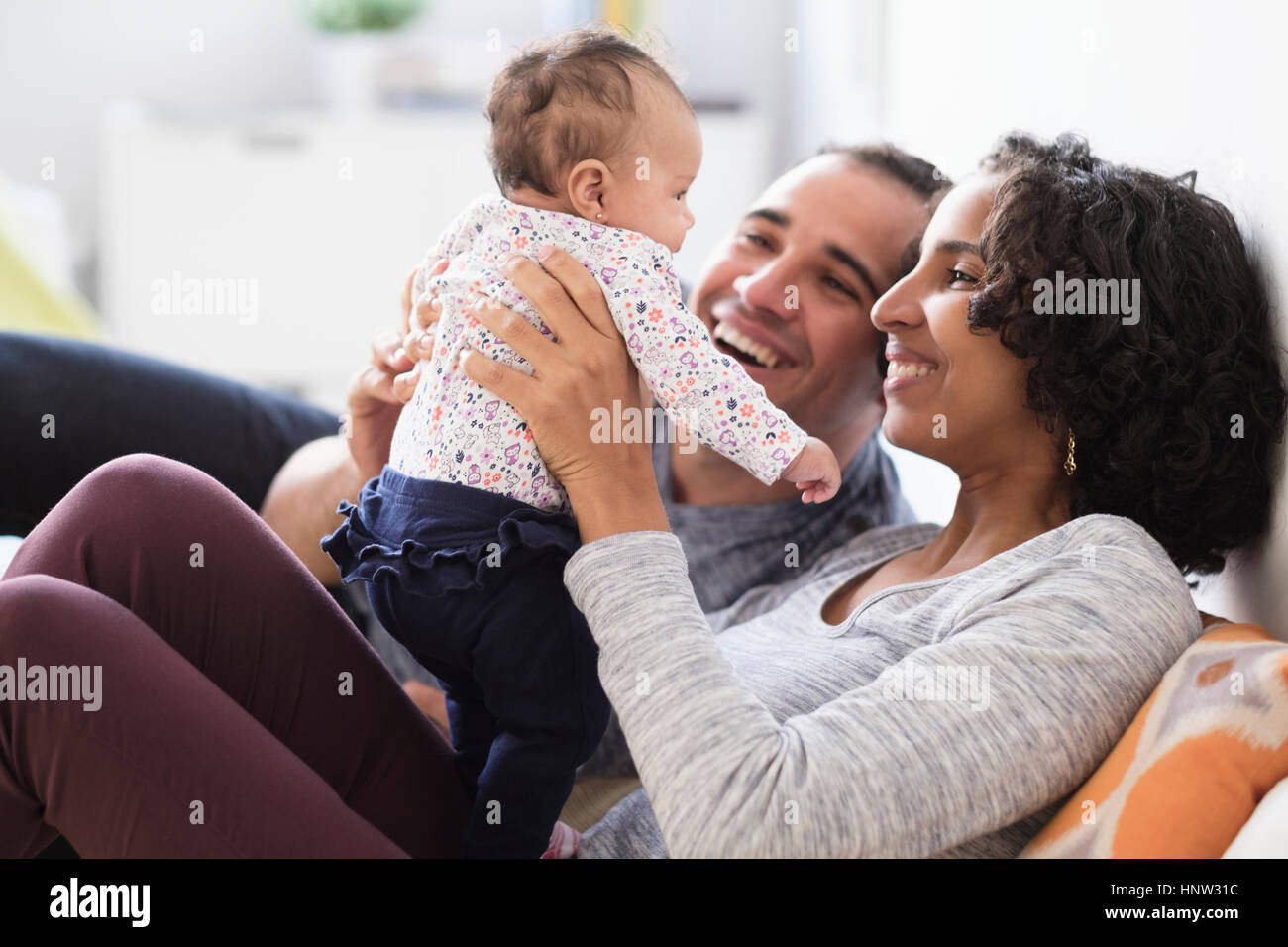 Hispanic mother and father playing with baby daughter Stock Photo