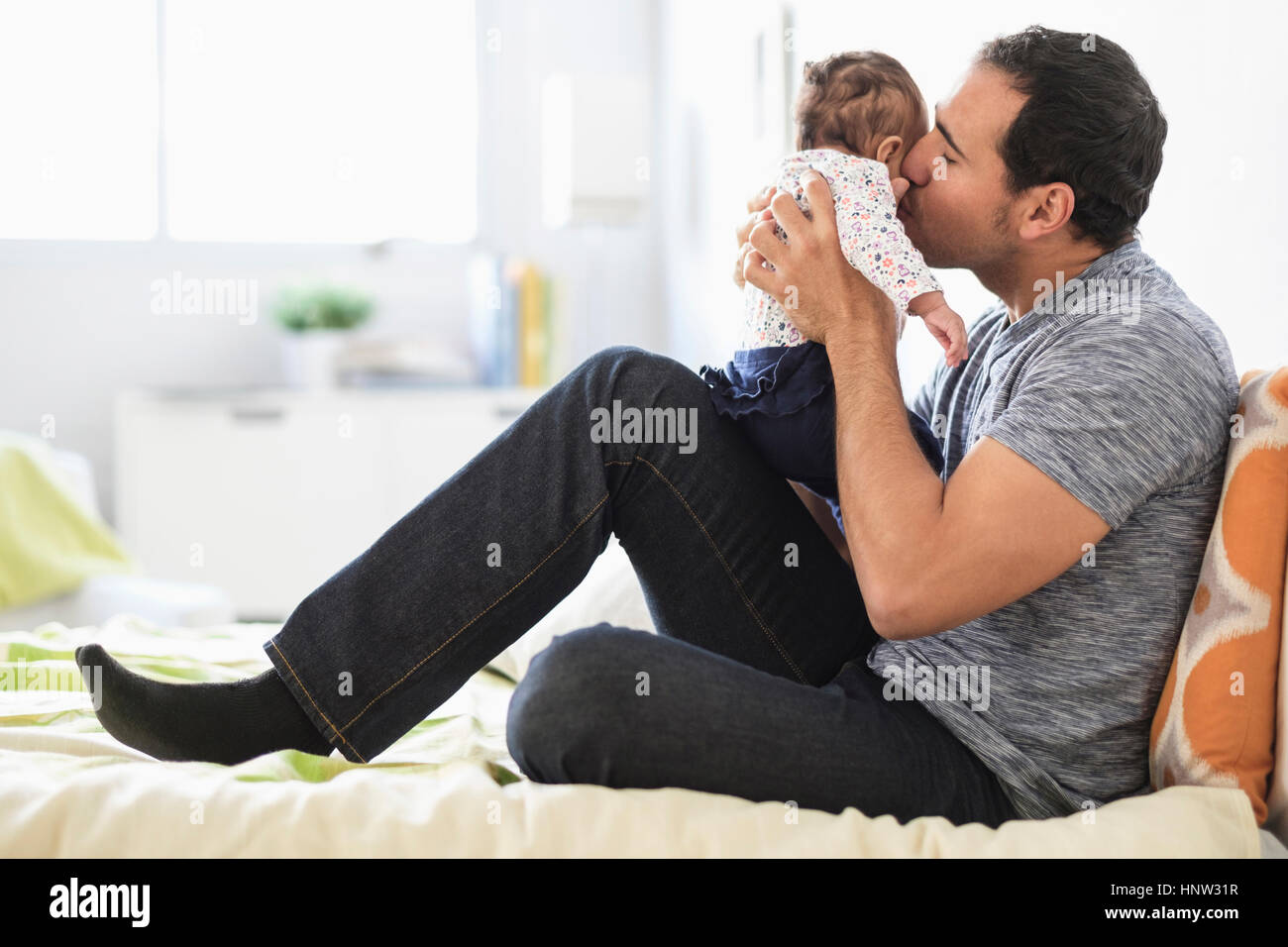 Hispanic father kissing baby daughter on cheek Stock Photo