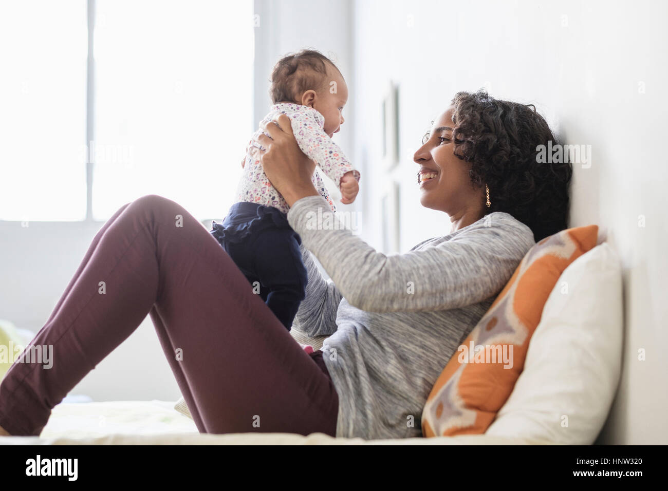 Hispanic mother playing with baby daughter on bed Stock Photo