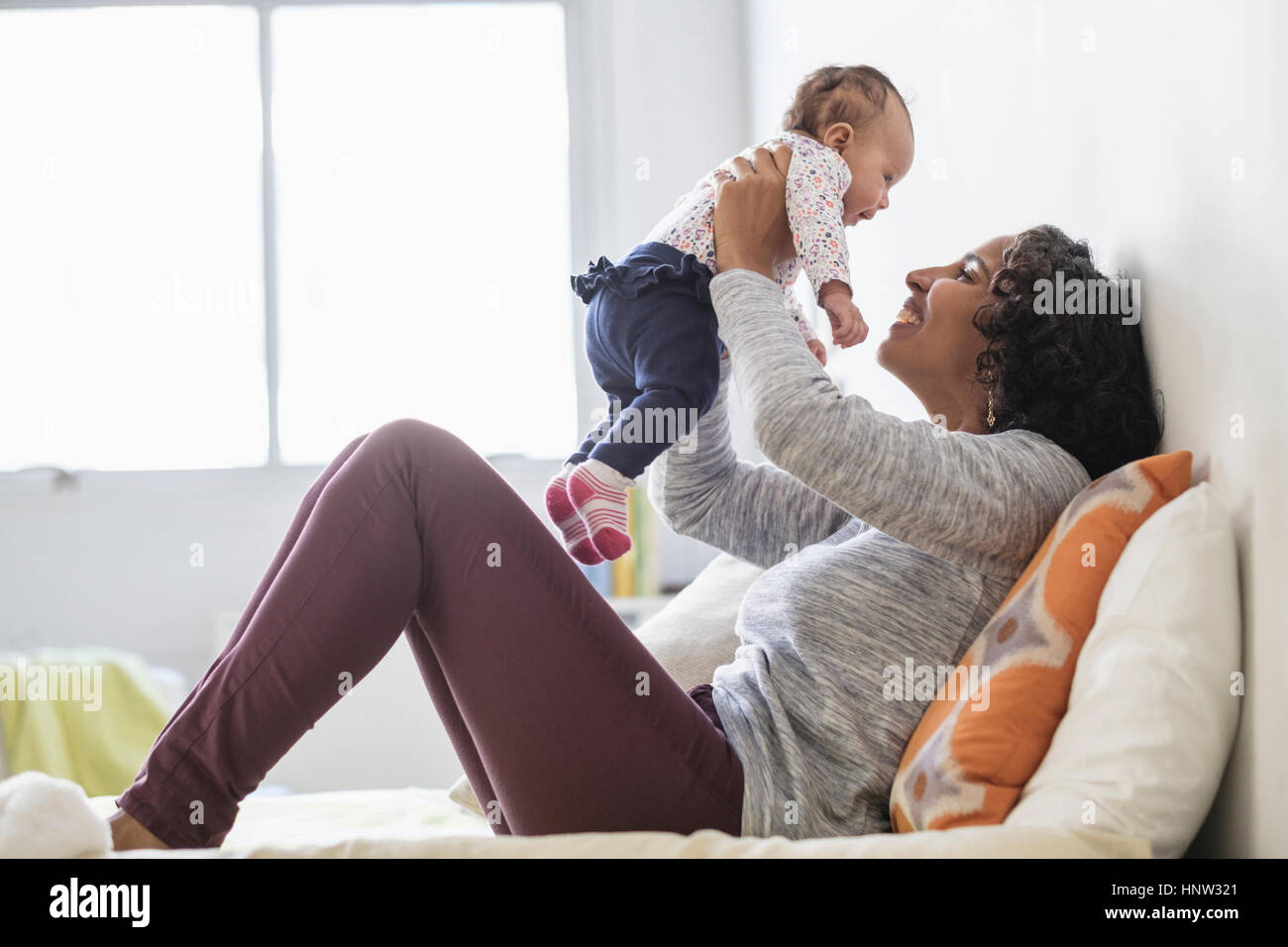 Hispanic mother playing with baby daughter on bed Stock Photo