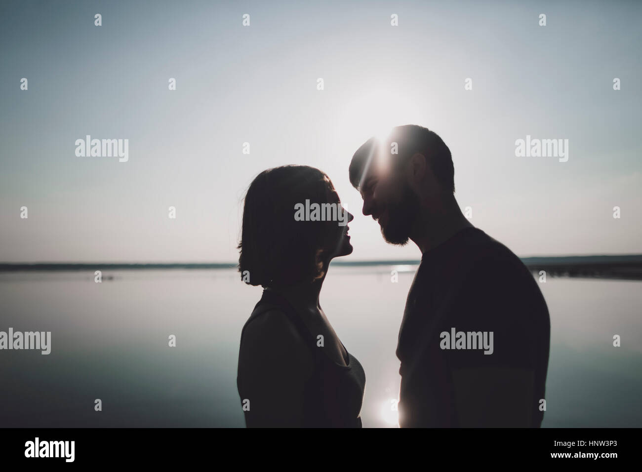 Silhouette of smiling Caucasian couple at lake Stock Photo
